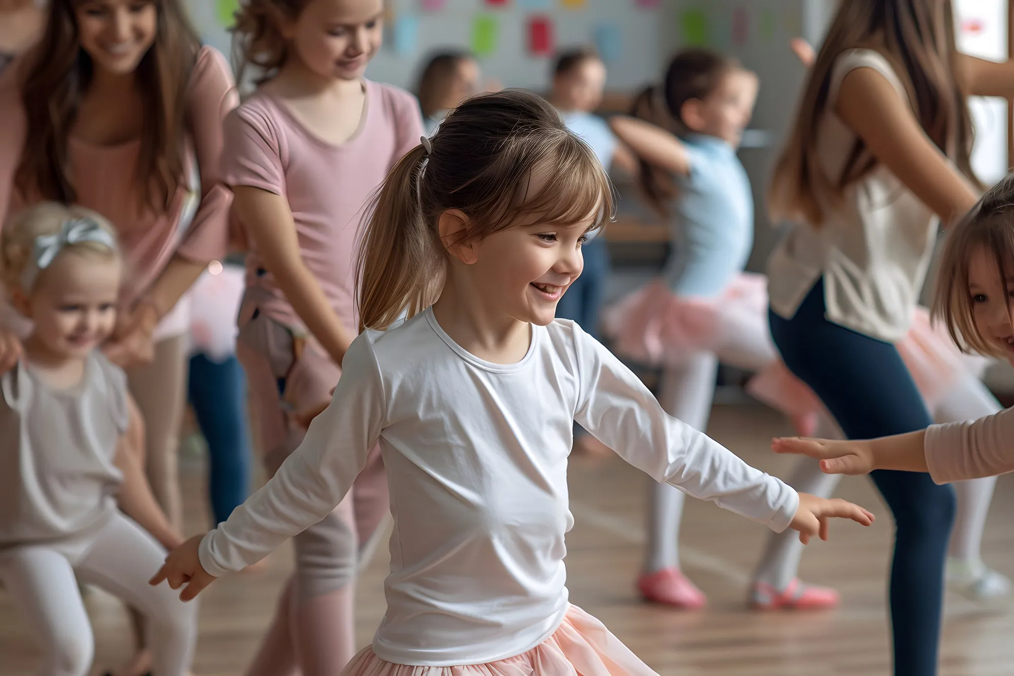 Kinder tanzen in einem hellen Saal, ein Mädchen in der Mitte lacht und breitet die Arme aus.
